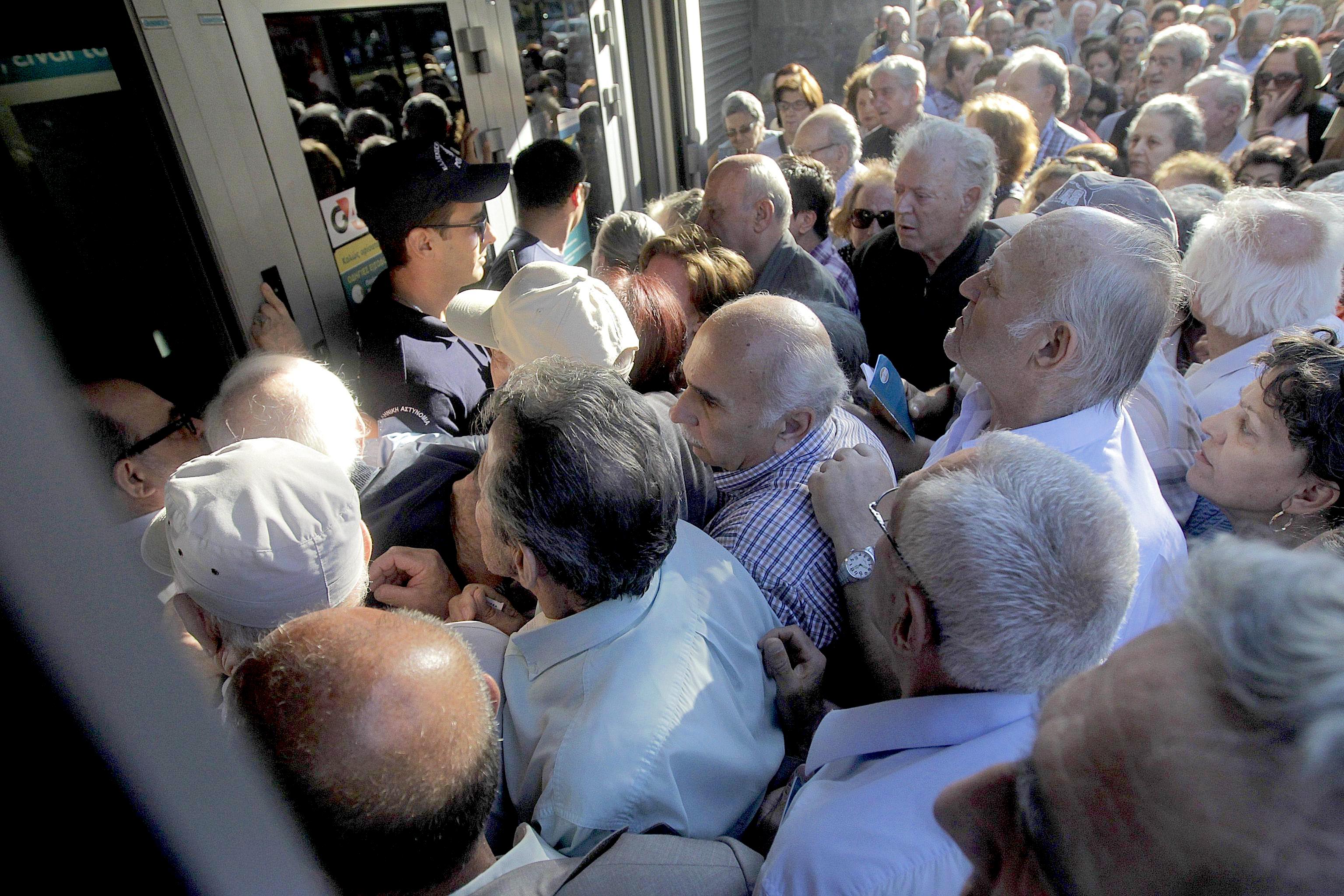 Pensioners who do not own ATM cards line up outside a bank branch to withdraw part of their pensions as a result of capital controls imposed by the Greek government