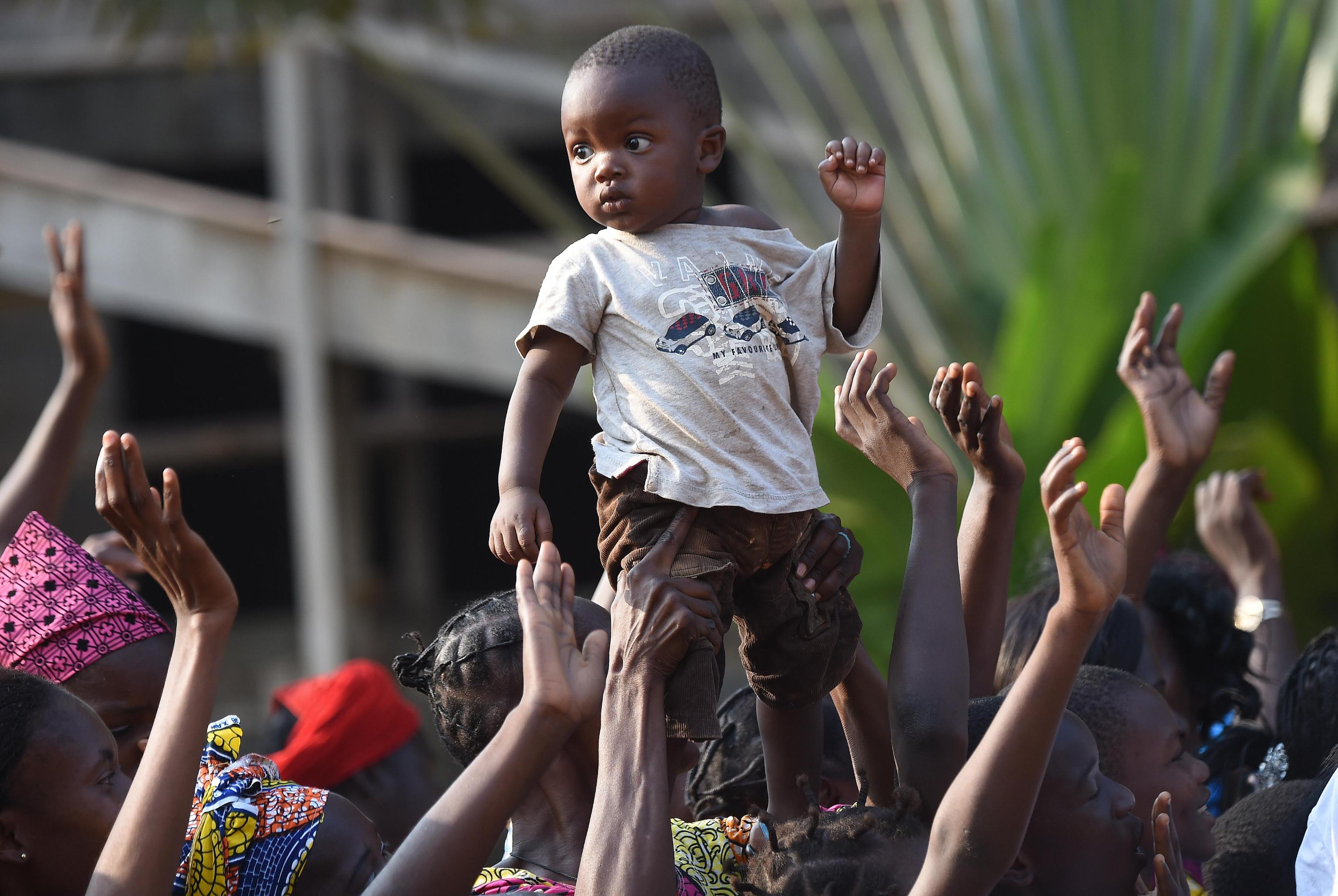 A boy is lifted by her mother at the arrival of Pope Francis at a meeting with evangelical communities at the evangelical theological school in Bangui