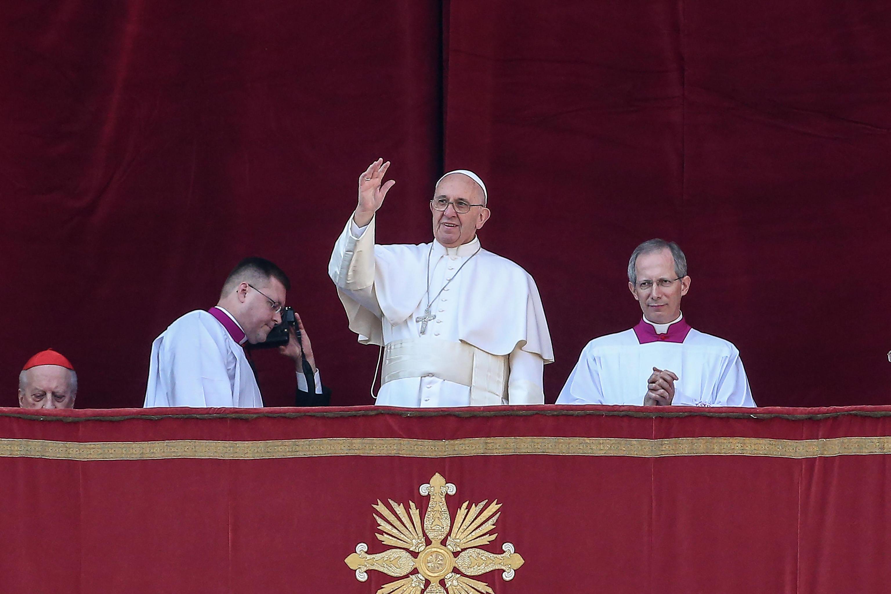 Pope Francis waves to the faithful as he delivers the traditional Urbi et Orbi Christmas Day message from the central balcony of St. Peters Basilica in Vatican City