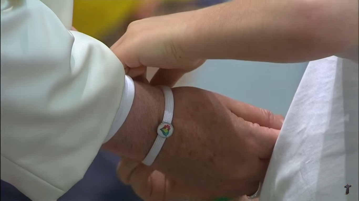 Un enfant de la "Fabrique de la paix" passe un bracelet de l'asosciation au poignet du pape François, capture CTV