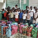 Des jeunes haïtiens devant de sacs contenant l’aide humanitaire © AED