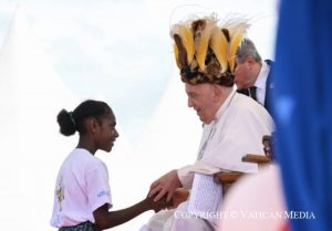 Le pape avec une coiffe traditionnelle salue une jeune © Vatican Media